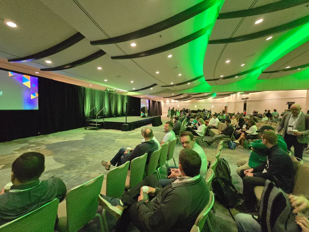 A screen displays &ldquo;veeamon Welcome to Partner Kickoff&rdquo; with colorful abstract shapes in the background.